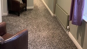 A hallway with patterned carpet, a brown armchair, and a purple curtain. - George & Dragon (Chester)