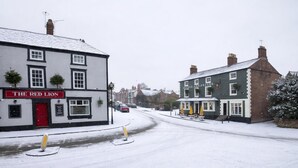 A street with buildings, including a pub named 'The Red Lion' and another with a sign 'S. George & Dragon.' - George & Dragon (Chester)