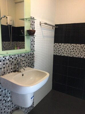 A bathroom with a white sink, a glass shelf with toiletries, and a mirror. - Hugpua Hotel (Pua)