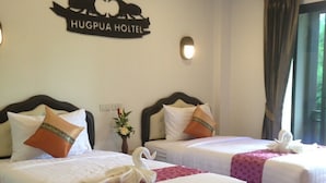 A hotel room with two beds, each with white bedding and decorative pillows. A sign above the beds reads "HUGPUA HOLTEL". - Hugpua Hotel (Pua)