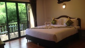 A hotel room with a bed, a balcony with a table and chairs, and a sign on the wall. - Hugpua Hotel (Pua)