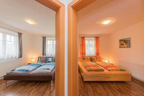 A room with two beds, wooden flooring, and a painting on the wall. - Landhaus Hochkönig (Muehlbach Am Hochkoenig)