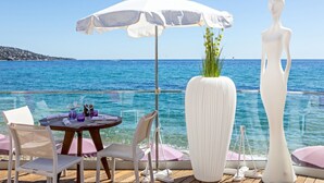 A dining area with a table, chairs, and a large white vase with flowers.