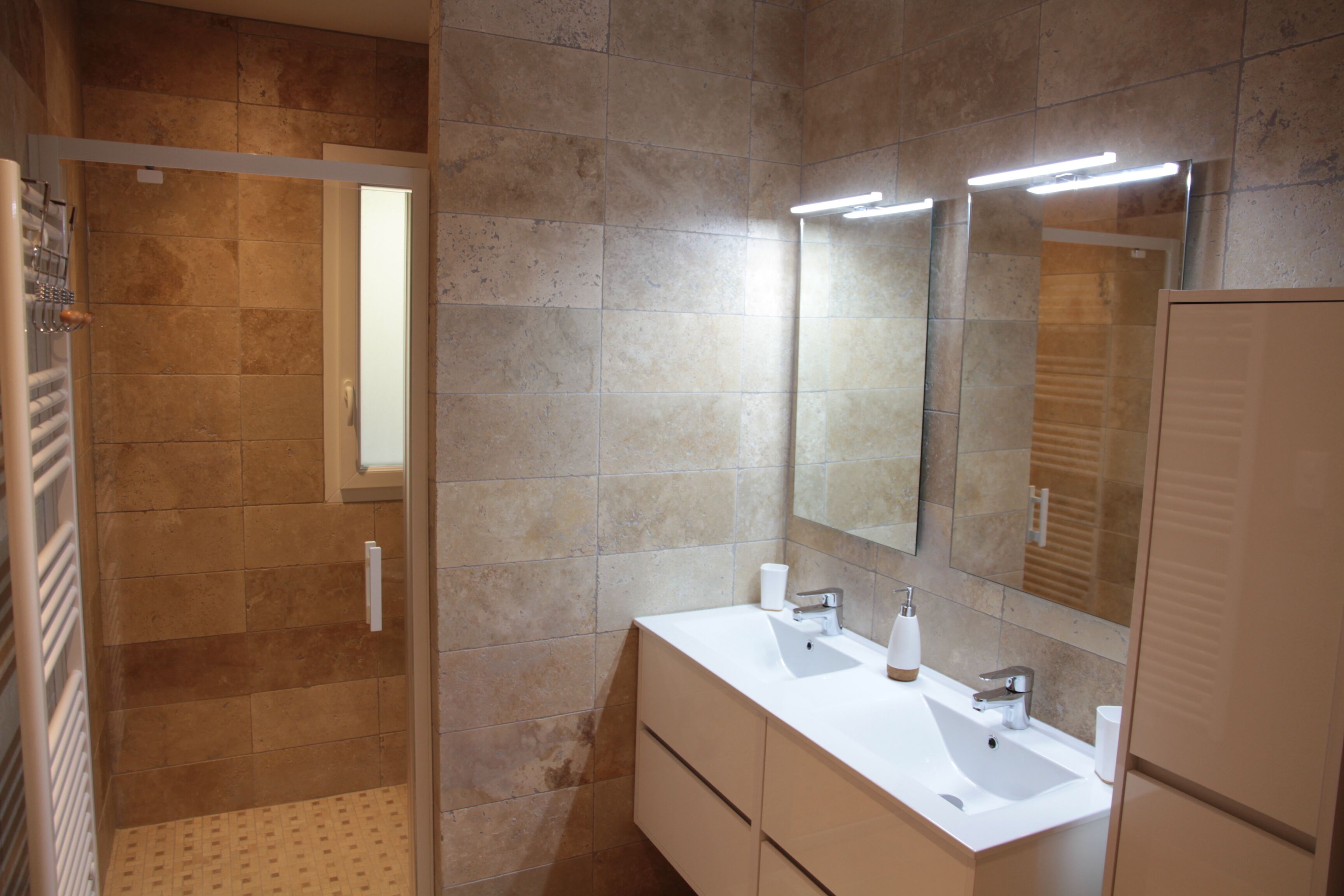 A modern bathroom with a walk-in shower, a large mirror, and a white vanity with a sink.