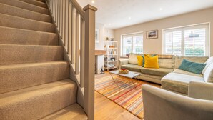 A staircase leading to a living area with a sofa, a coffee table, and a bookshelf. - Sherbet Cottage, South Creake, Norfolk (Fakenham)
