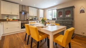 A modern kitchen with white cabinetry, a dining table set for four, and a gray cabinet with glass doors. - Sherbet Cottage, South Creake, Norfolk (Fakenham)