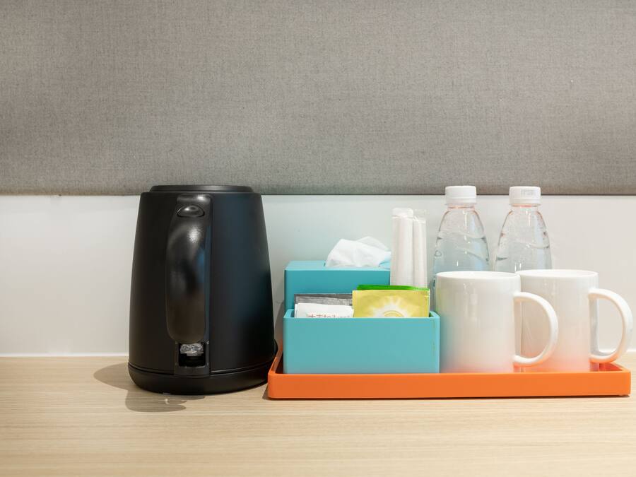 A coffee maker, a tissue box, a mug, and a water bottle on a tray.