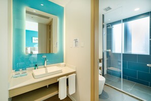A modern bathroom with a large mirror, white sink, and a glass-enclosed shower area. - Holiday Inn Express Shanghai Zhangjiang by IHG (Shanghai)