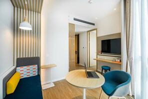 A modern hotel room with a bed, a round table with a laptop, a blue chair, a TV, and a wooden partition. - Holiday Inn Express Shanghai Zhangjiang by IHG (Shanghai)