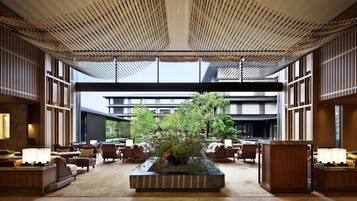 A spacious lobby with a central water feature, seating areas, and a modern ceiling design.