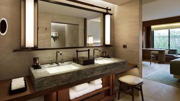Un baño moderno con dos lavamanos, un espejo grande y una zona de estar con una silla.
