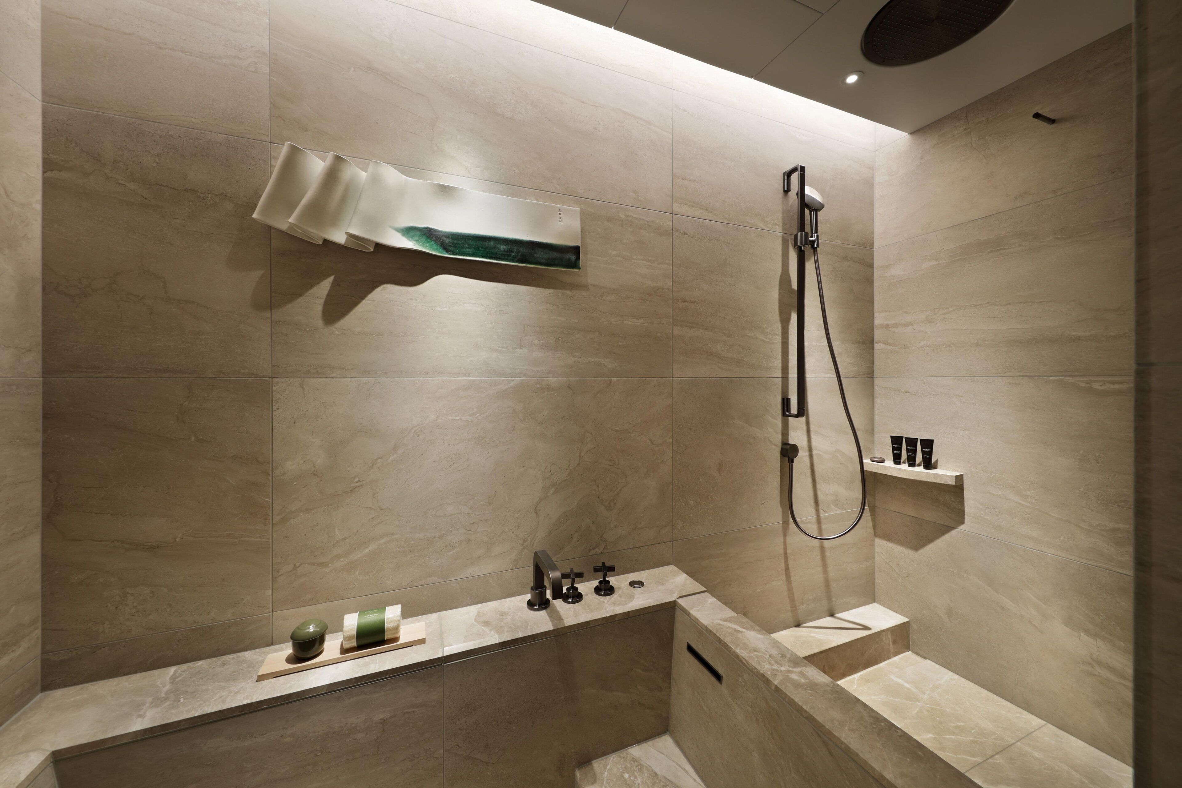 A modern bathroom with a freestanding bathtub, a showerhead, and a shelf with toiletries.