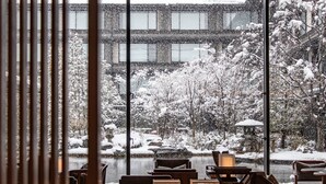 A view through a window of a snow-covered outdoor area with a pond, surrounded by trees and a building in the background. - HOTEL THE MITSUI KYOTO, a Luxury Collection Hotel & Spa (Kyoto)