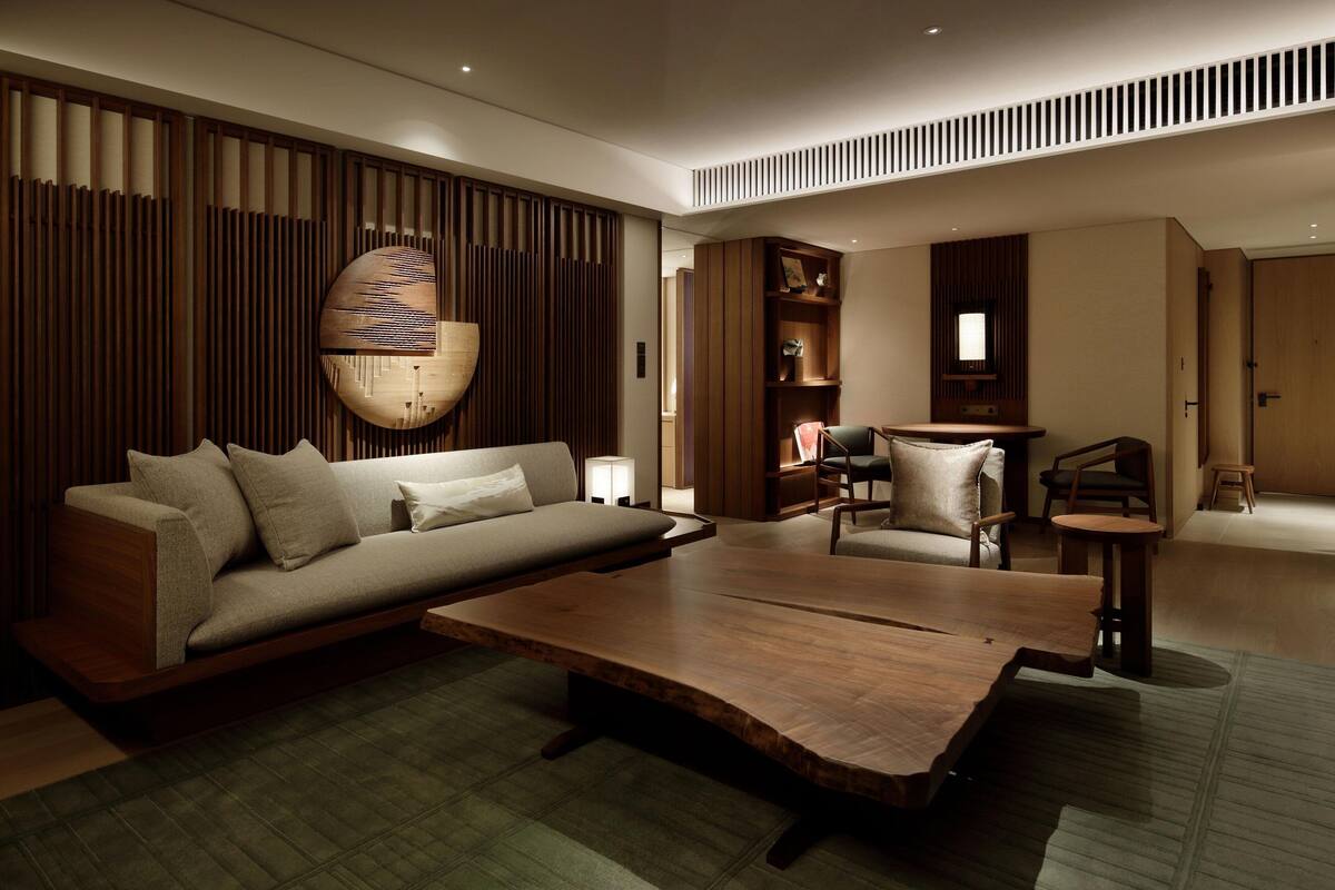 A modern living room with a sofa, a wooden coffee table, and a dining area with a small table and chairs.