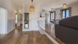 A modern interior with a wooden floor, white walls, and a dark sofa. There are pendant lights and a door with a white railing. - appartement  Serra  : Calvi centre, 300m de la page et du port terrasse bbq (Calvi)