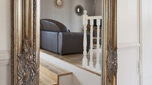 A room with a large mirror reflecting a staircase, a sofa, and a ceiling light fixture. - appartement  Serra  : Calvi centre, 300m de la page et du port terrasse bbq (Calvi)