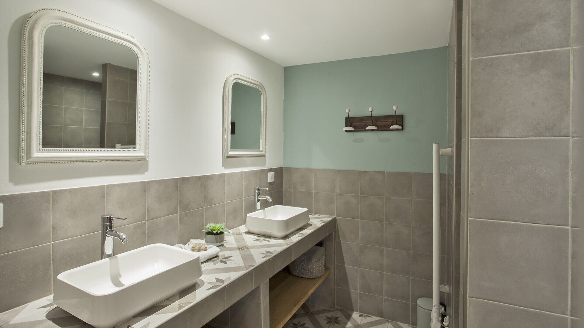 Een moderne badkamer met twee wastafels, een grote spiegel en een douchehoek.
