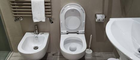 A bathroom with a bidet, a toilet, and a bathtub.