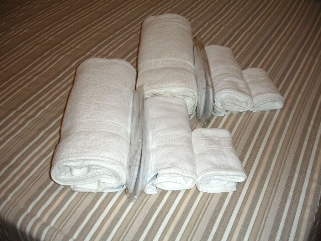 A bed with striped bedding and four neatly folded white towels.