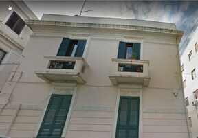 Un edificio con dos balcones, cada uno con barandilla y planta en maceta.
