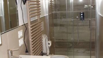 A modern bathroom with a glass-enclosed shower, a large sink, and a towel rack.