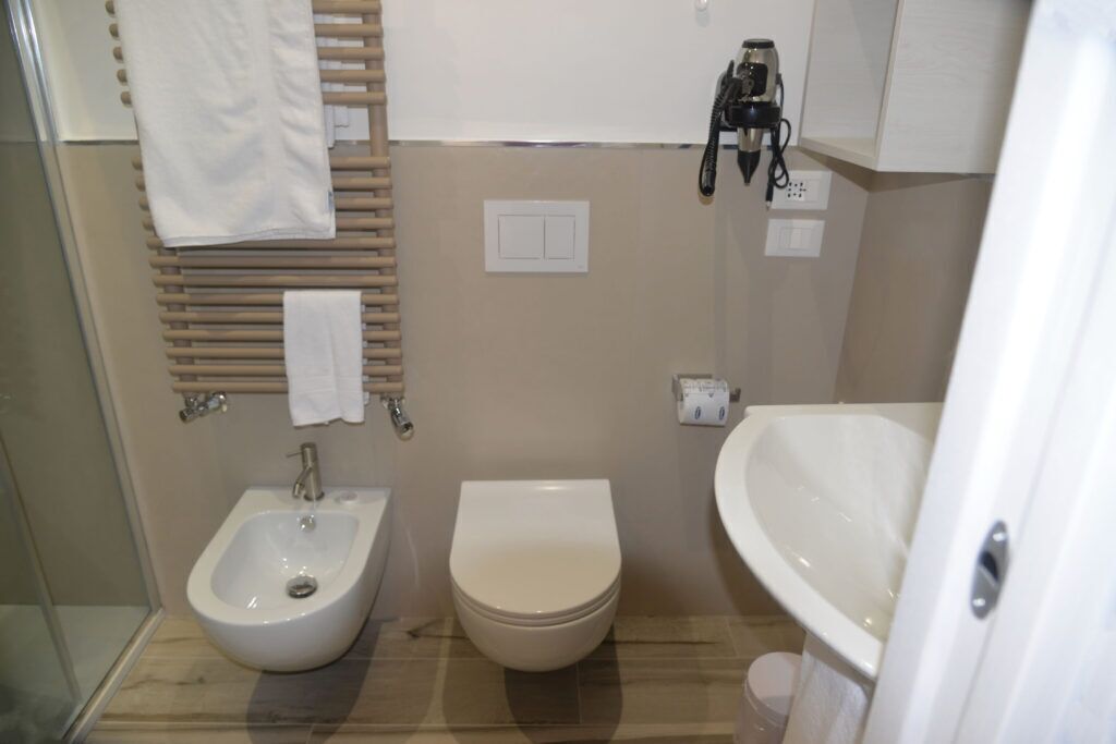 A small bathroom with a bidet, toilet, and sink.