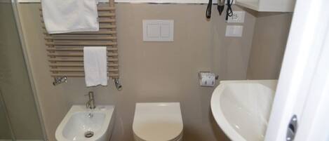 A small bathroom with a bidet, toilet, and sink.