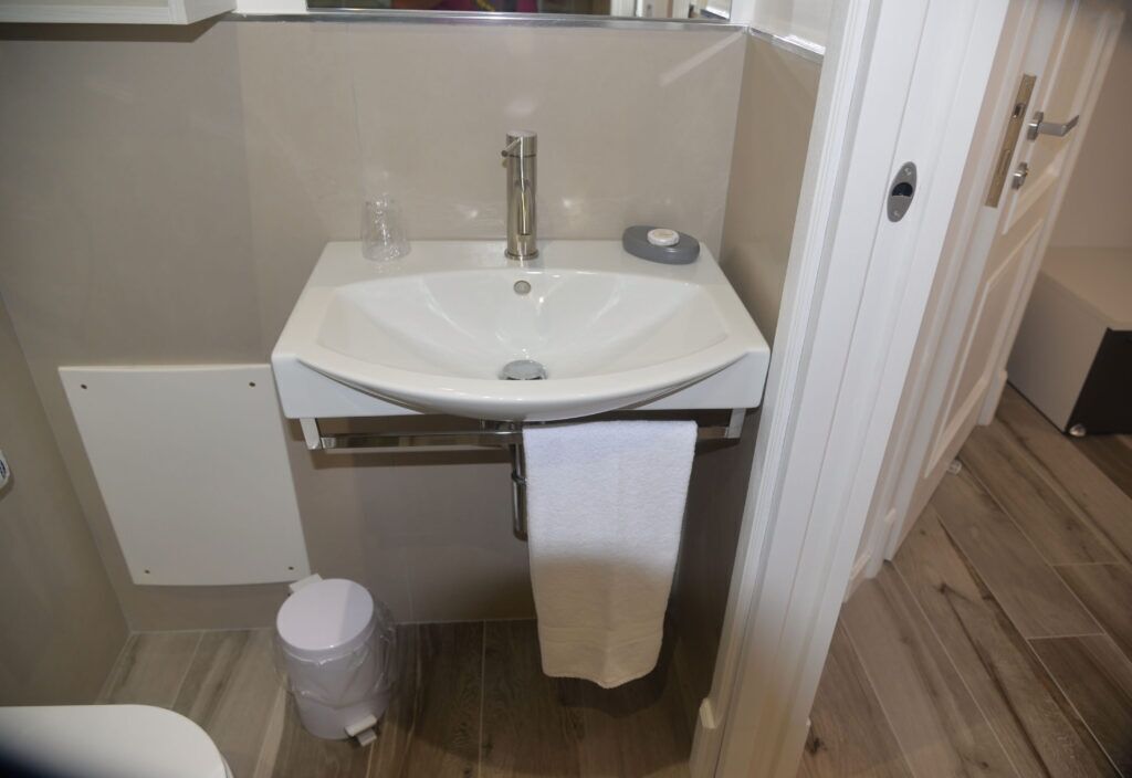 Un bagno con lavandino bianco, uno specchio e un water.