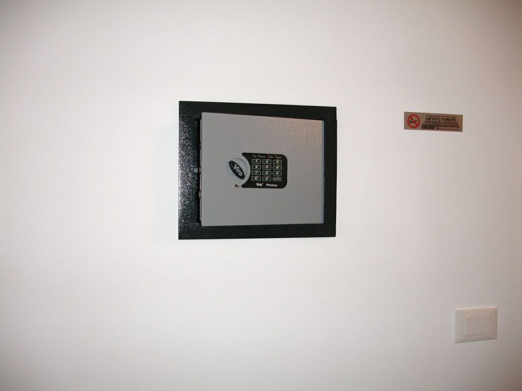 Un marco con una foto de un panel de control de seguridad en una pared blanca, con un cartel que indica zona prohibida para fumadores.