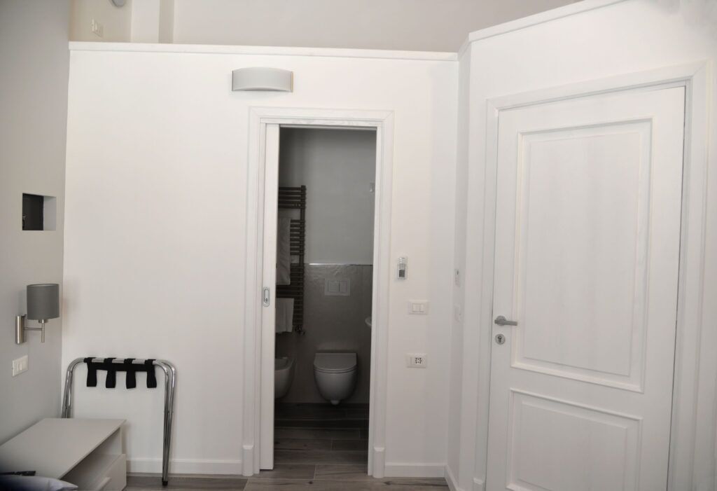 A narrow hallway with a door on the right and a bathroom visible through an open door.
