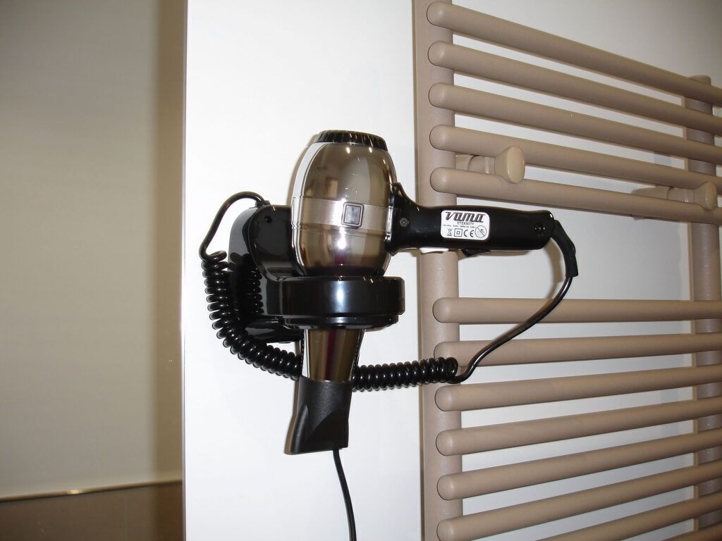 A hair dryer attached to a beige radiator.