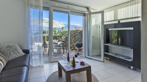 A modern living room with a sofa, a coffee table, and a TV. - Mare, appart avec jardin et bbq, vue mer et montagne, plage et port à 2 pas (Calvi)