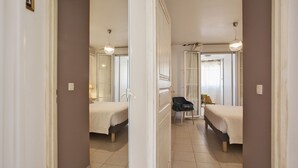 A narrow hallway leading to two bedrooms with beds, a chair, and a door. - Mare, appart avec jardin et bbq, vue mer et montagne, plage et port à 2 pas (Calvi)