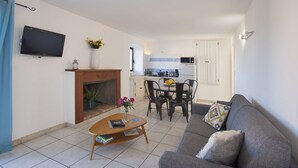 Un salon avec une cheminée, un coin repas avec une table et des chaises, et une cuisine équipée d’un four à micro-ondes et d’une cuisinière.