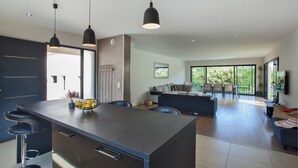 Una cocina moderna con una isla central, taburetes de bar e iluminación colgante.
