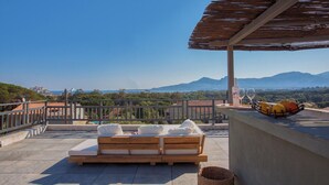 Una terraza en la azotea con un banco de madera, una cesta de mimbre y una botella de vino.