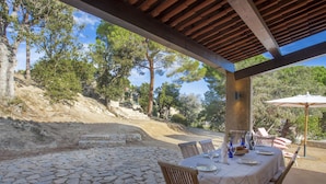 Un patio al aire libre con suelo de piedra, mesas y sillas de madera.