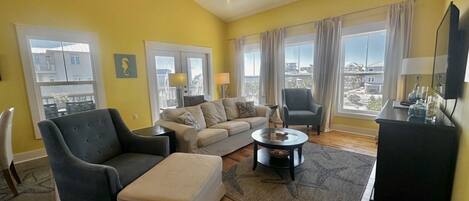 A living room with a sofa, armchair, ottoman, coffee table, and a ceiling fan.
