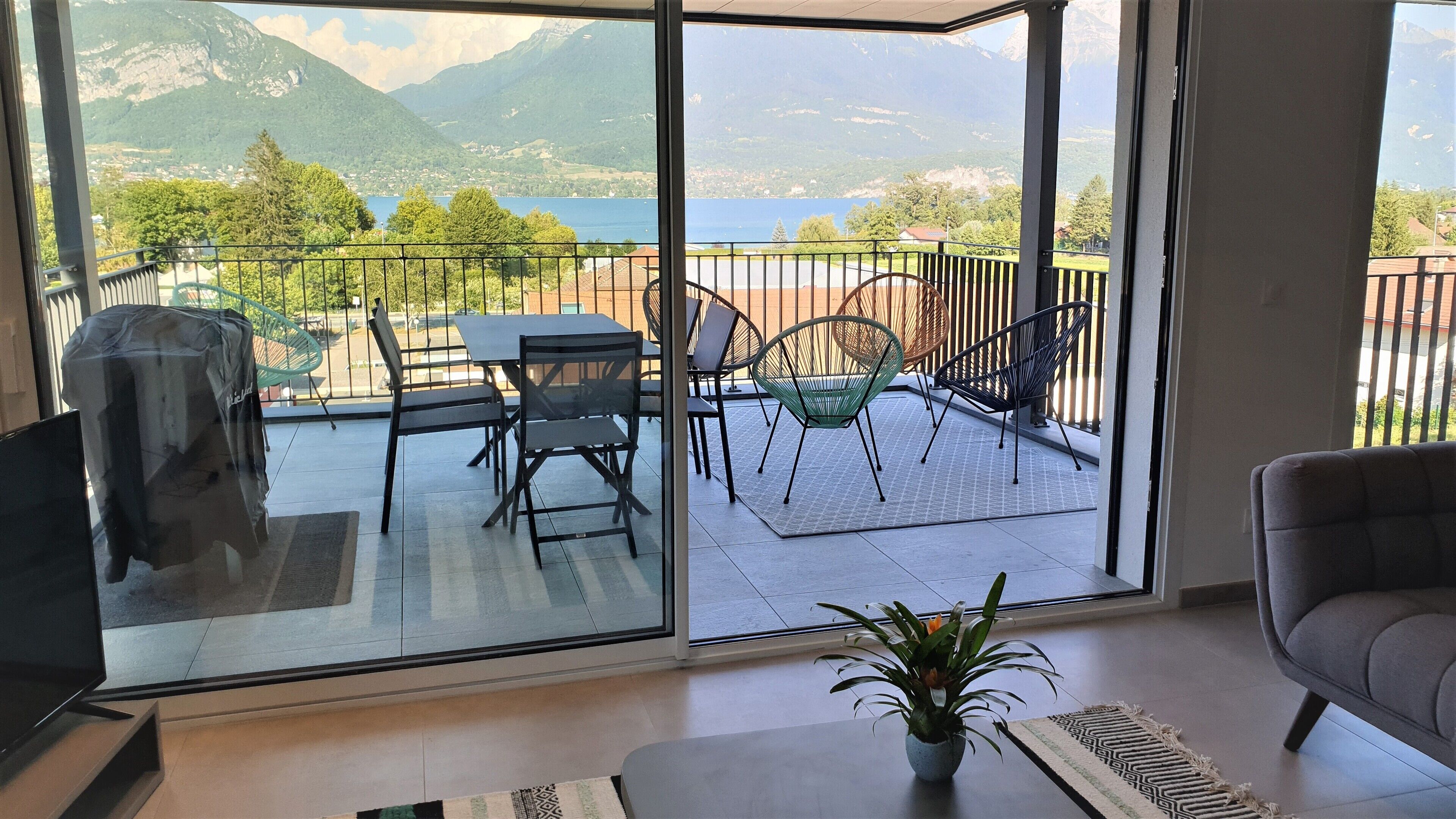 A balcony with a table and chairs, a potted plant, and a sofa.