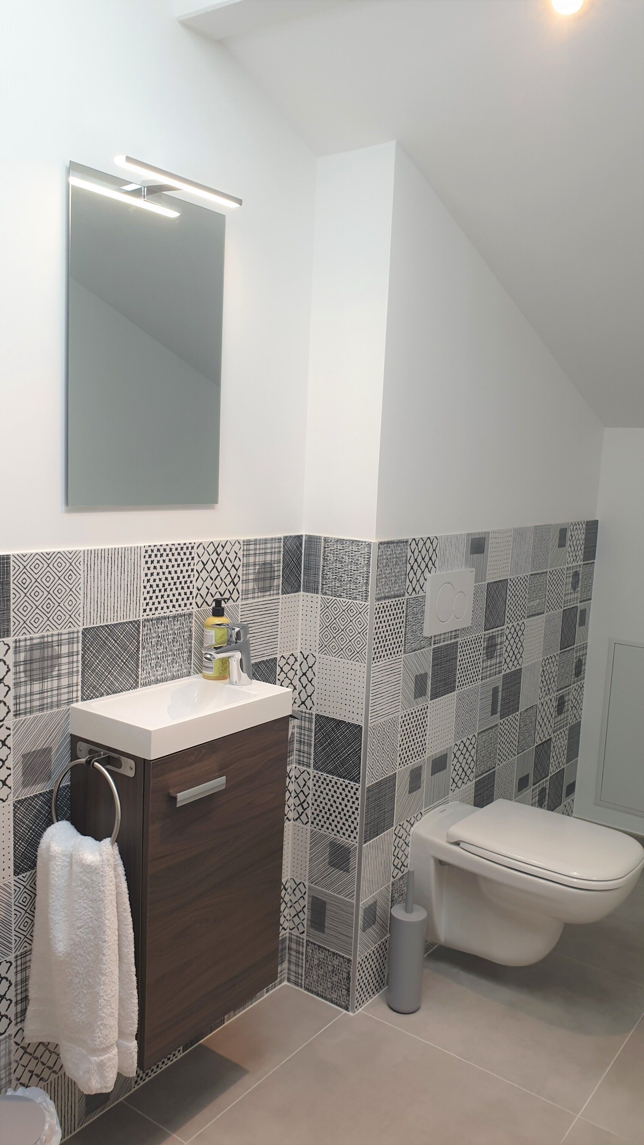 Un baño moderno con tocador blanco, toallero y retrete.