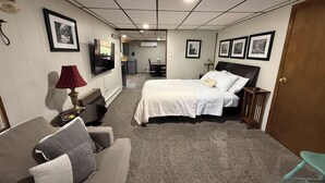 Een hotelkamer met een bed, een televisie, een bureau, een stoel, een lamp en een deur.