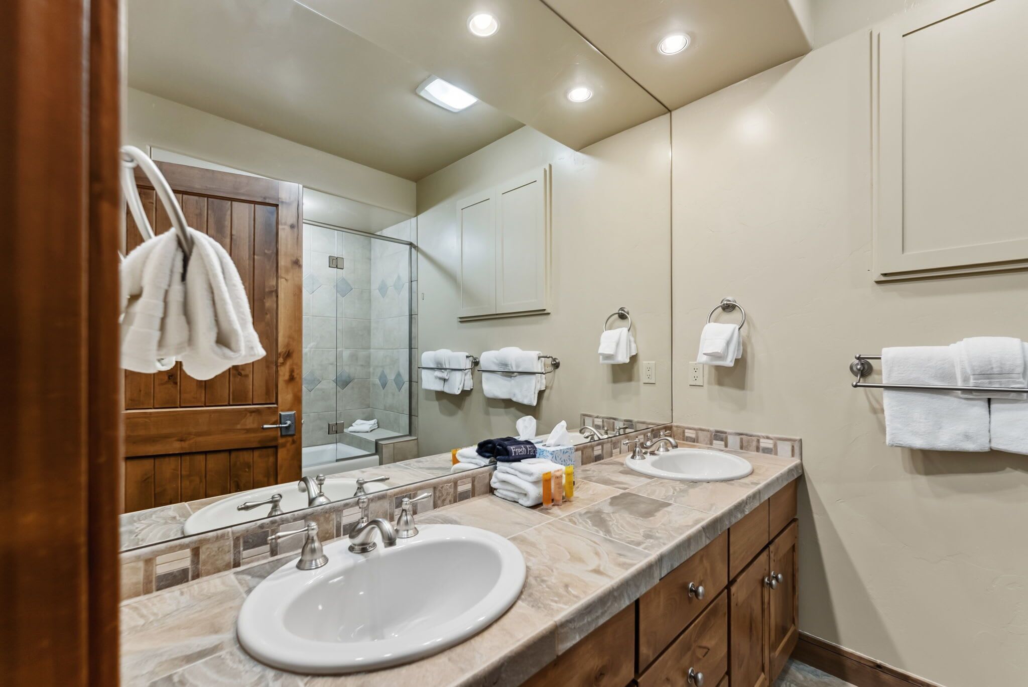 Une salle de bain moderne avec deux lavabos, un grand miroir et des meubles en bois.
