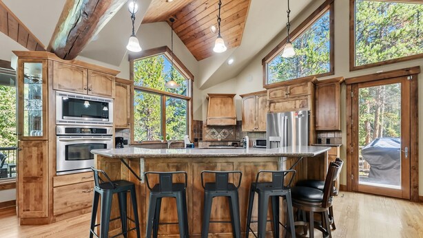 A spacious kitchen with wooden cabinets, a large island with bar stools, and a view of the outdoors.