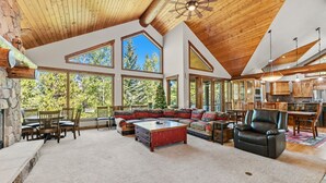 A spacious living area with a high ceiling, large windows, and a cozy seating arrangement.