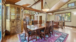 A spacious dining area with a wooden table and chairs, surrounded by wooden cabinets and a large window.