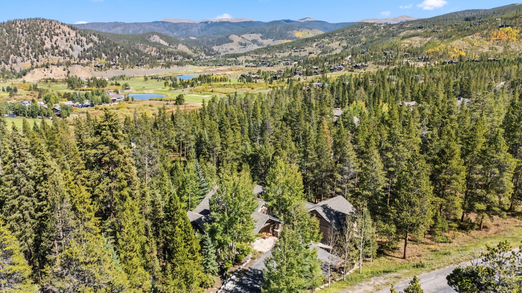 A mountainous landscape with dense forests, a golf course, and scattered houses.