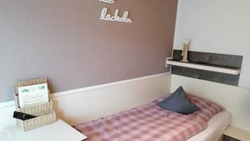 A bedroom with a bed, a bedside table, a wall-mounted shelf, and a wall decoration.