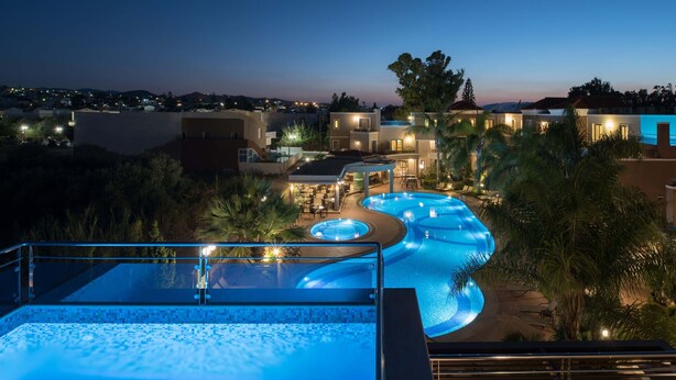 Ett semesterhotell med en stor infinitypool, utomhusmöbler och utsikt över det omgivande landskapet.