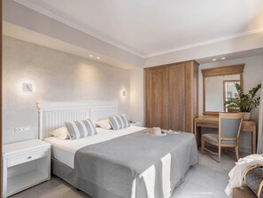 A bedroom with a bed, bedside tables, a desk, a chair, and a mirror. - Okeanis Golden Resort (Chania)
