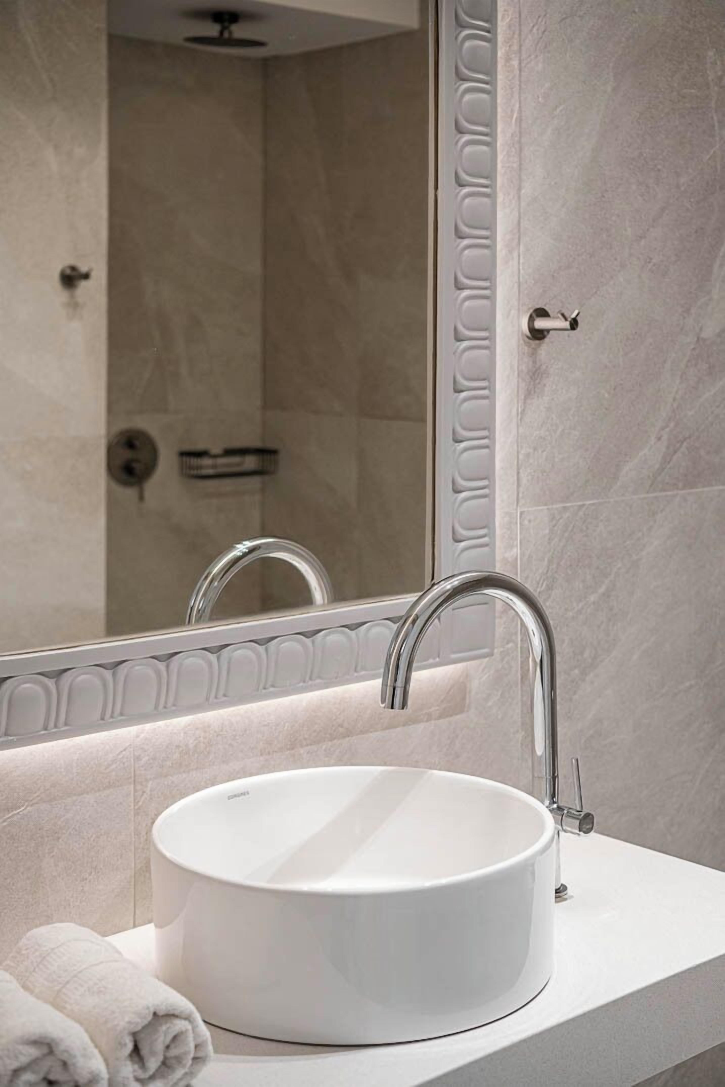 A bathroom with a white sink, a mirror, and a shower area.